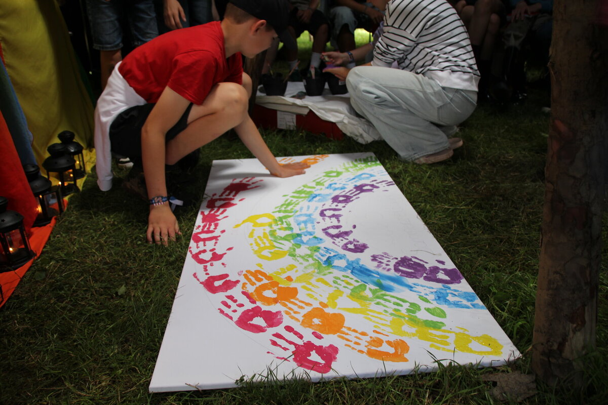 Kind macht bunten Handabdruck auf Leinwand im Regenbogen-Design