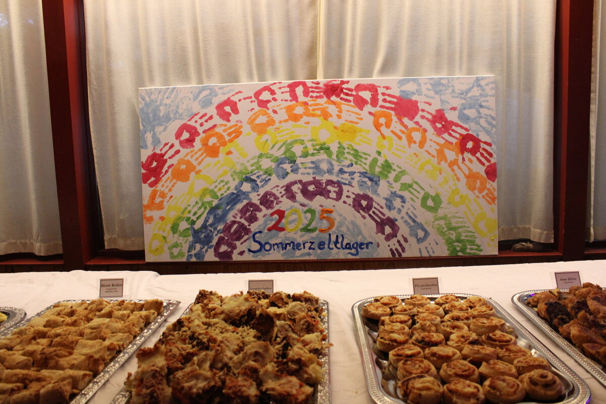 Regenbogen-Handabdruck-Leinwand mit Aufschrift 2025 Sommerzeltlager über einem Buffet