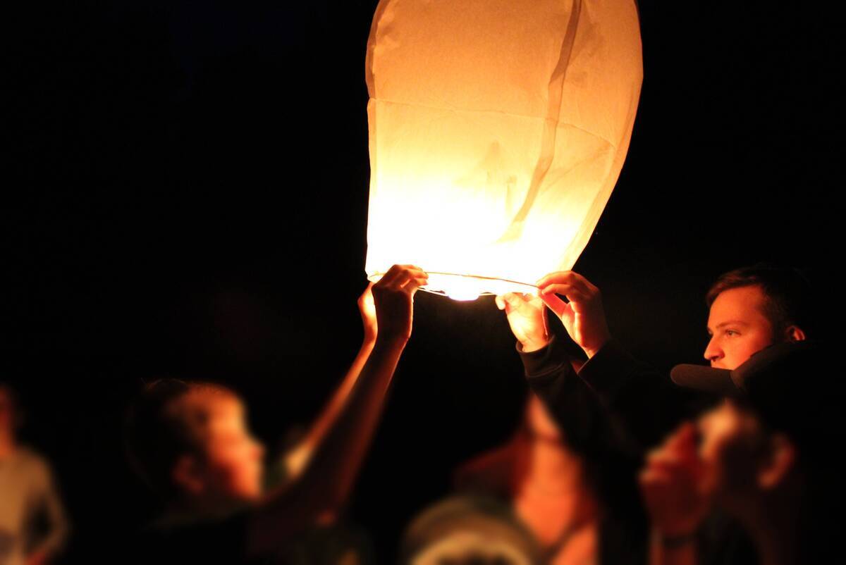 Kinder und Betreuer lassen gemeinsam eine Himmelslaterne in die Nacht steigen