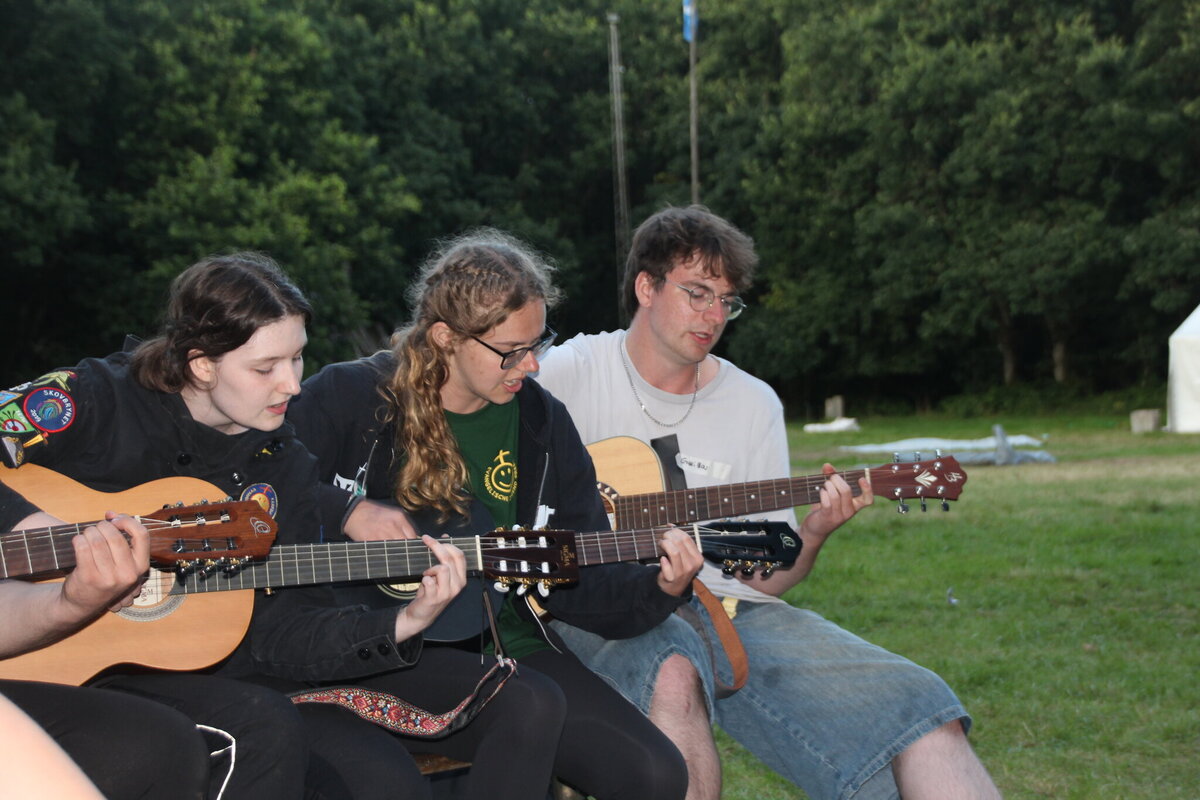 Drei Jugendliche spielen abends Gitarre und singen gemeinsam
